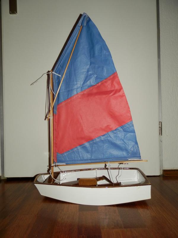 Optimist jeugdzelboot met het tweede zeil, waarbij de giek lager uitkomt en de spriet de tophoek hogers opsteekt. Het zeiltje blijft zelfs zonder zeillatten aan het achterlijk mooi gevormd, en met een kunstmatig gevormde wind vormde het zich goed. Straks aan het water denk ik dat er met behulp van neerhouder, onderlijkstrekker en spriettakel een mooi trimbaar zeitje op deze modeloptimist staat!